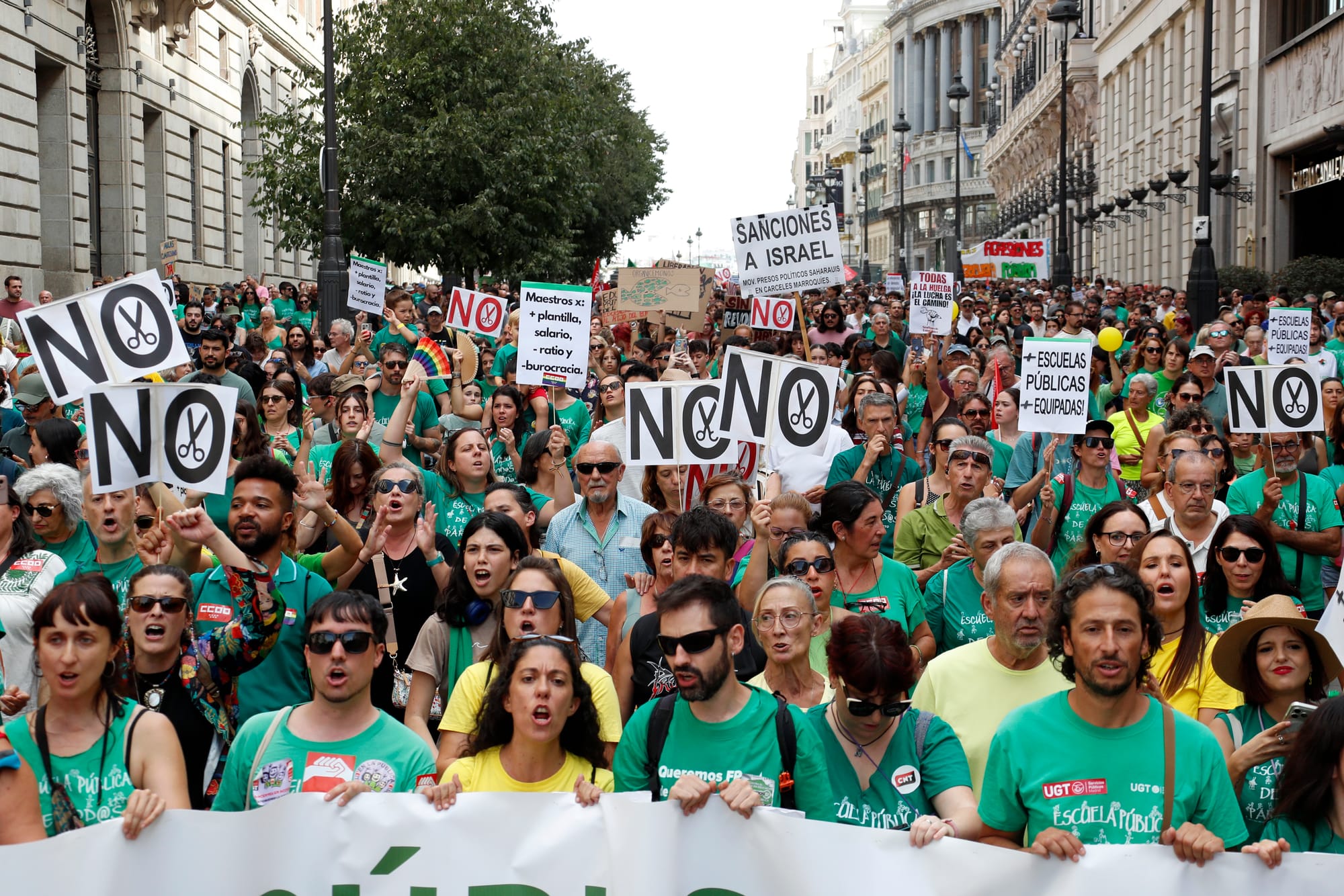 Multitud de manifestantes con camisetas verdes marchando por una calle céntrica de Madrid. En alto sostienen carteles con la palabra 'NO' junto al dibujo de unas tijeras y otras pancartas reclamando 'Escuelas públicas equipadas'.