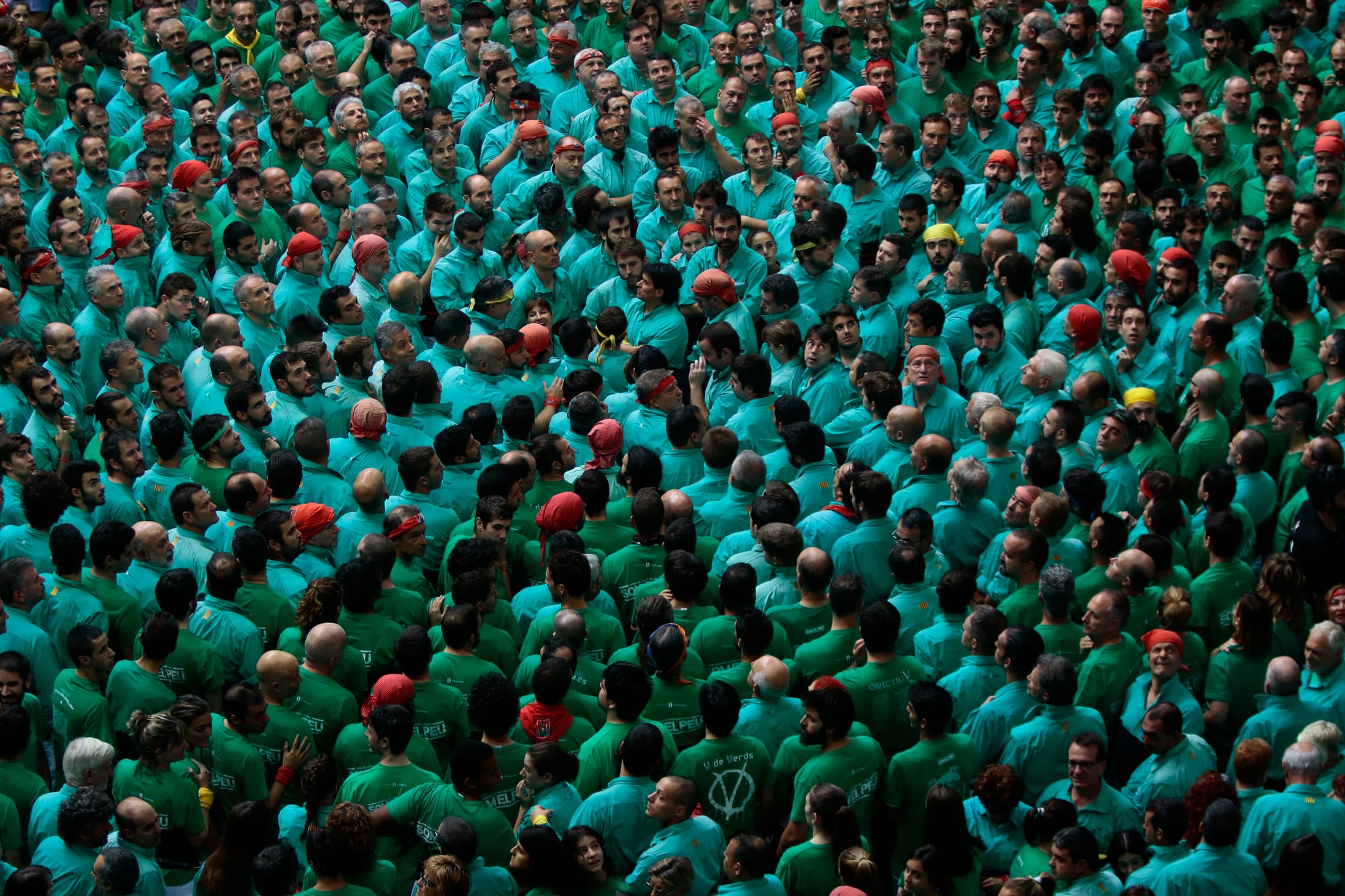 Rostros concentrados de varios castellers en la base de la estructura mirando hacia arriba mientras se preparan para soportar el peso de la torre.