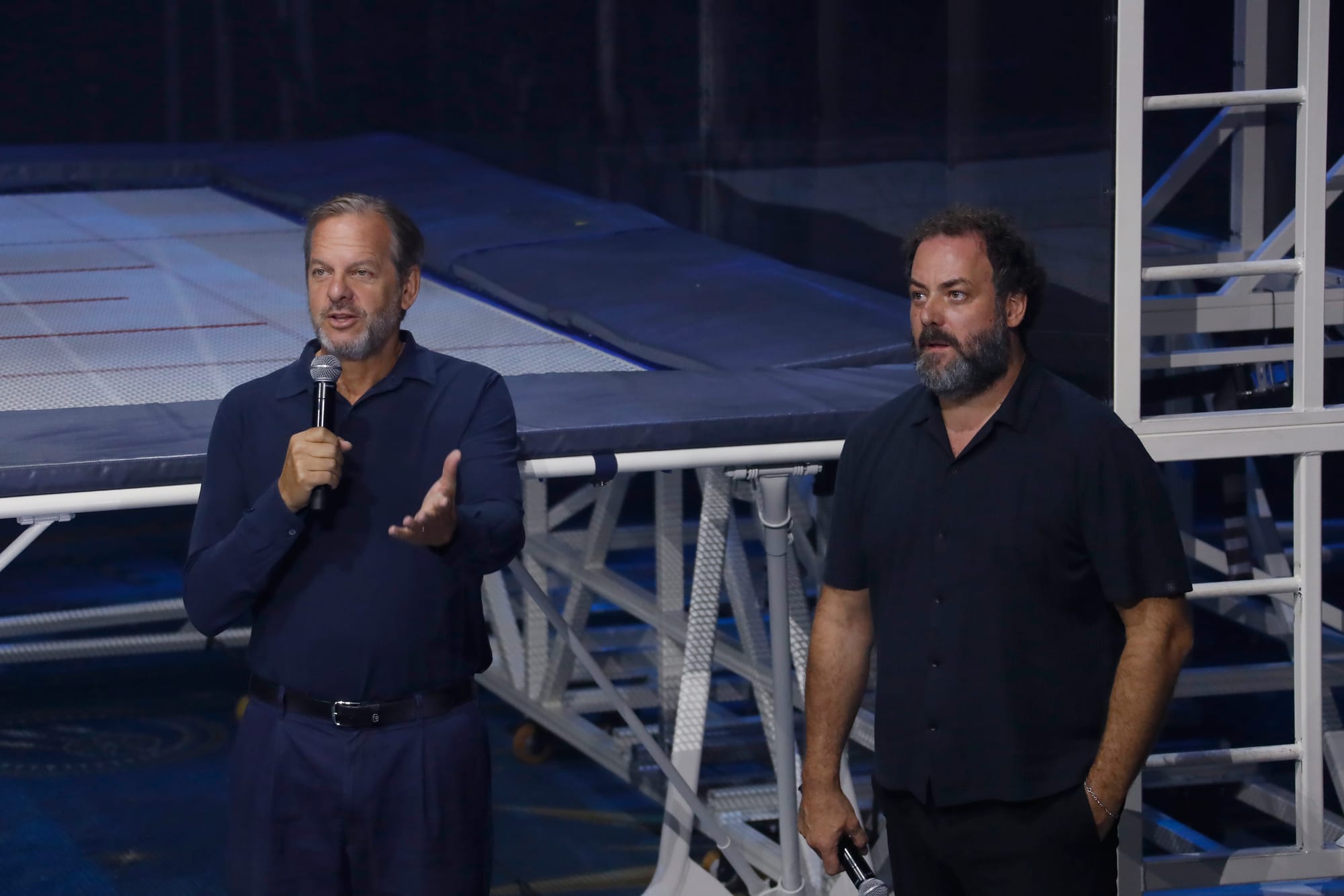 Fotografía de Marco Balich e Iñaki Fernández sobre el escenario sosteniendo micrófonos durante la presentación de 'The Island of Neverland'. Al fondo se observan las estructuras metálicas y las camas elásticas del montaje.