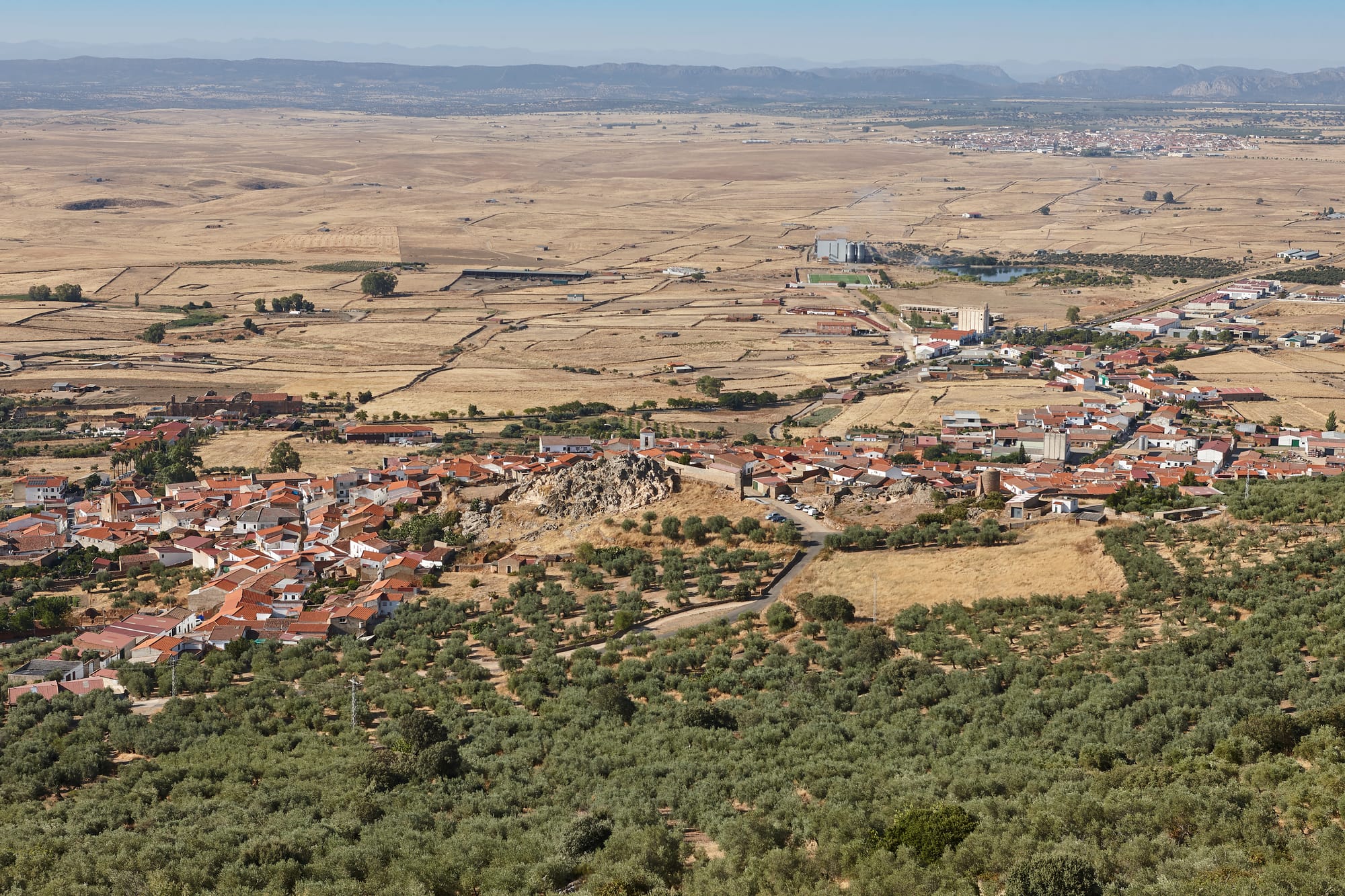 Vista panorámica de la localidad de Puebla de Alcocer, mostrando sus tradicionales casas blancas y edificios históricos integrados en el vasto paisaje de la llanura pacense en Extremadura.
