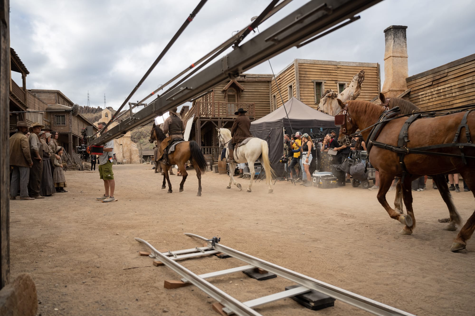 Imagen del rodaje de la película Trinidad mostrando una grúa de filmación y raíles de cámara en la calle principal de un poblado del Oeste con caballos y equipo técnico.