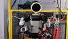 Fotografía en plano medio del robot humanoide Atlas en un laboratorio de pruebas, sujetando una punta de destornillador con la mano derecha y un taladro inalámbrico con la izquierda.