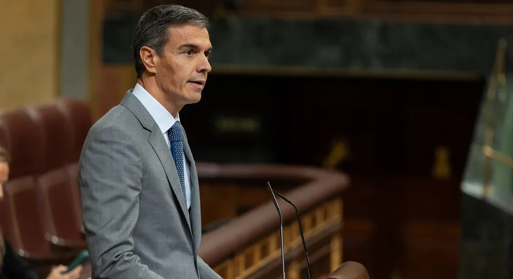 Fotografía en plano medio lateral del presidente del Gobierno, Pedro Sánchez, vistiendo traje gris y corbata azul, hablando con gesto serio desde la tribuna del Congreso de los Diputados.