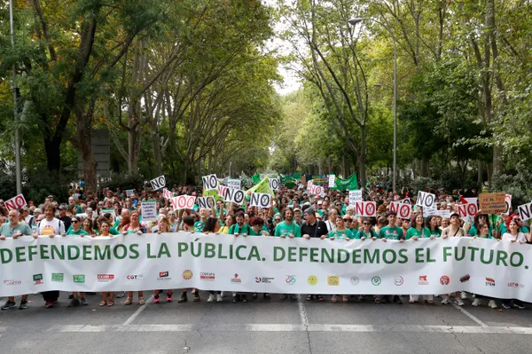 Multitud de manifestantes marchando por Paseo del Prado en Madrid. En primera línea sostienen una gran pancarta blanca con letras verdes que dice 'DEFENDEMOS LA PÚBLICA. DEFENDEMOS EL FUTURO'